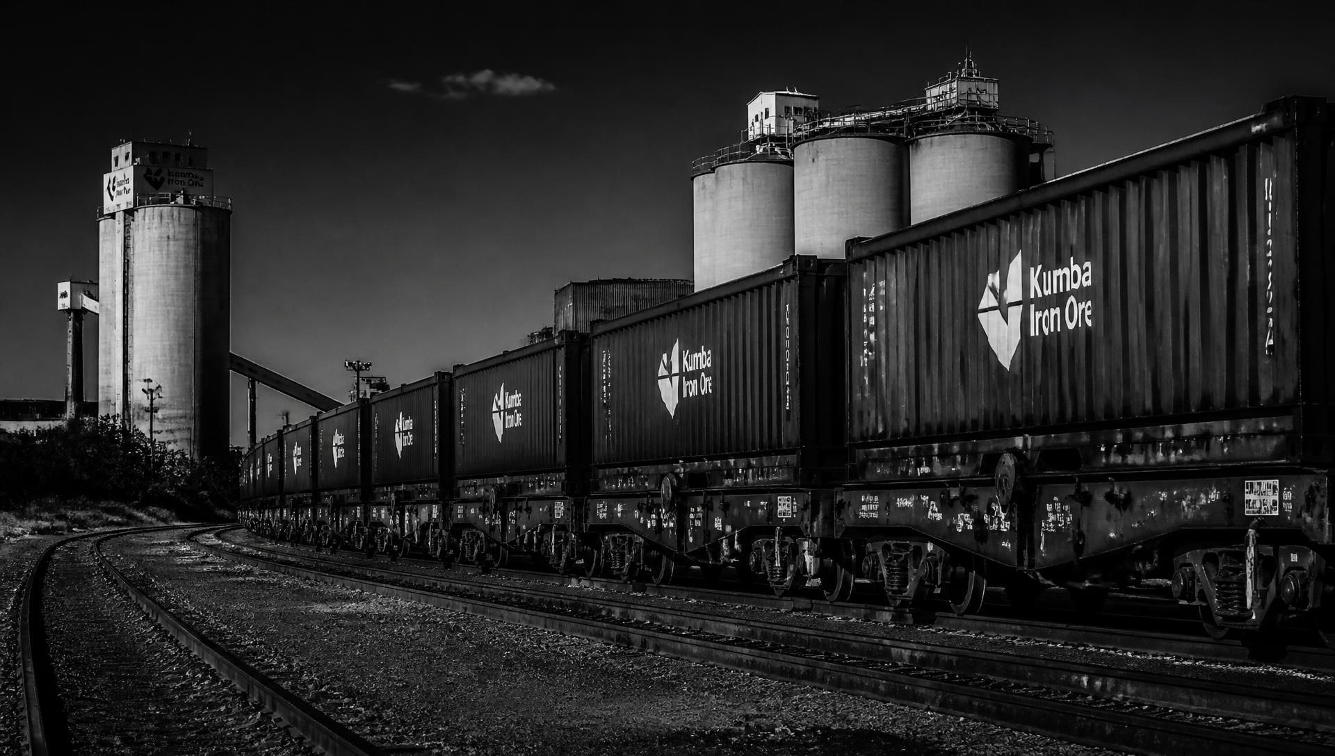 Freight rail yard with stacked mineral bulk containers in warm ochre dusk light